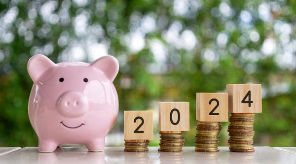 piggy bank with coins stacked next to it, blocks on top that read 2024
