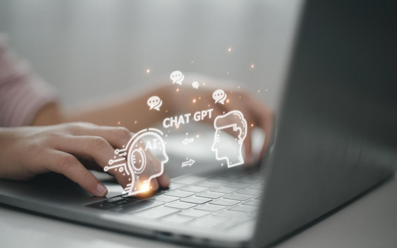 A person typing on a laptop with a graphic of a robot and person with ChatGPT written between them